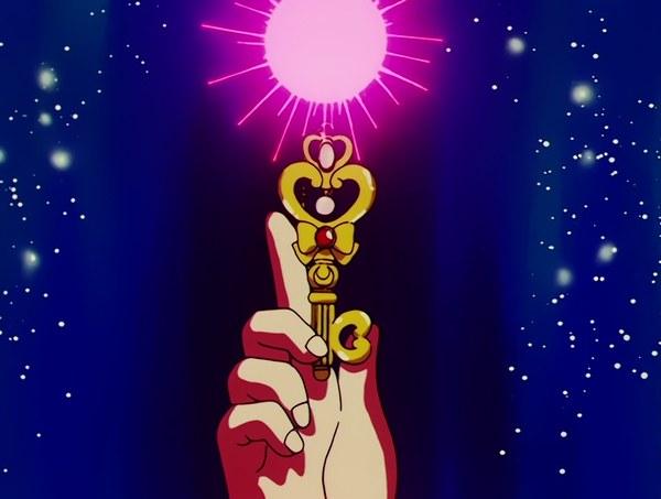 The Space-Time Key held up against a field of stars, its heart-shaped head lit from above.