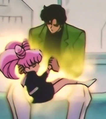 Mamoru in his green jacket holding Chibiusa across his lap, a yellow glow around his hands