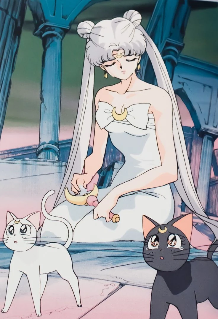 Queen Serenity in a white gown, seated among the pale columns of the Moon palace with her crescent wand, and Artemis and Luna looking up from the floor in front of her