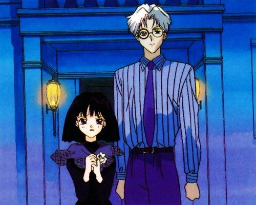 Hotaru and Professor Tomoe standing together in the blue-lit entrance hall of their house, she in a dark dress holding a small flower, he in a striped shirt and tie