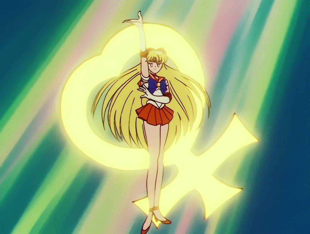 Sailor Venus landing the final pose of her transformation, the Venus glyph burning gold behind her.