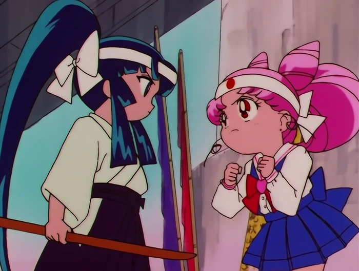 Chibiusa in a kendo headband with her fists up and her chin lifted, squaring up to a taller dark-haired girl in kendo dress holding a shinai