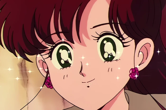 a close-up of Makoto smiling with her eyes bright, rose earrings and sparkles catching the light around her