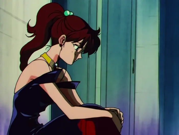 Makoto alone in a dark evening dress, knees drawn up, head down against a wall