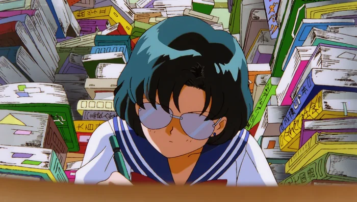 Ami at a desk in a wall of books, glasses on, working