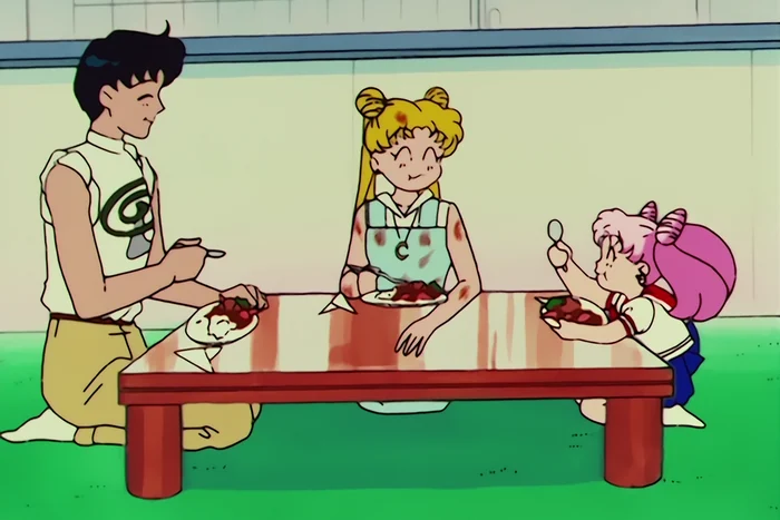 Mamoru, Usagi and Chibiusa kneeling round a low red table, eating and smiling, with food splashed over the table and Usagi