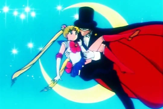 Tuxedo Mask carrying Sailor Moon in his arms in front of a crescent moon, his red-lined cape streaming out behind them