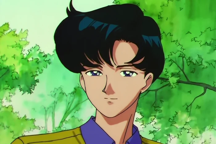 Mamoru in daylight under green trees, smiling a little