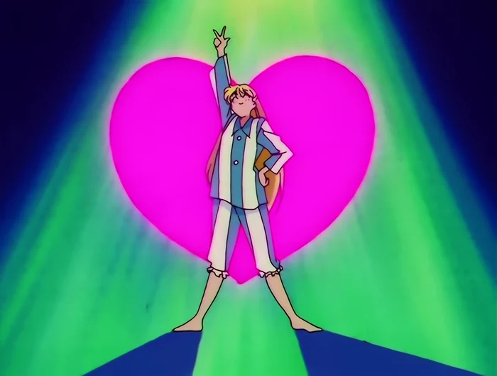 Minako in striped pyjamas striking a pose in front of an enormous pink heart under green spotlights, one arm thrown up in a V sign