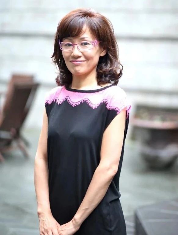Naoko Takeuchi in recent years, in pink glasses and a black top with a pink lace collar