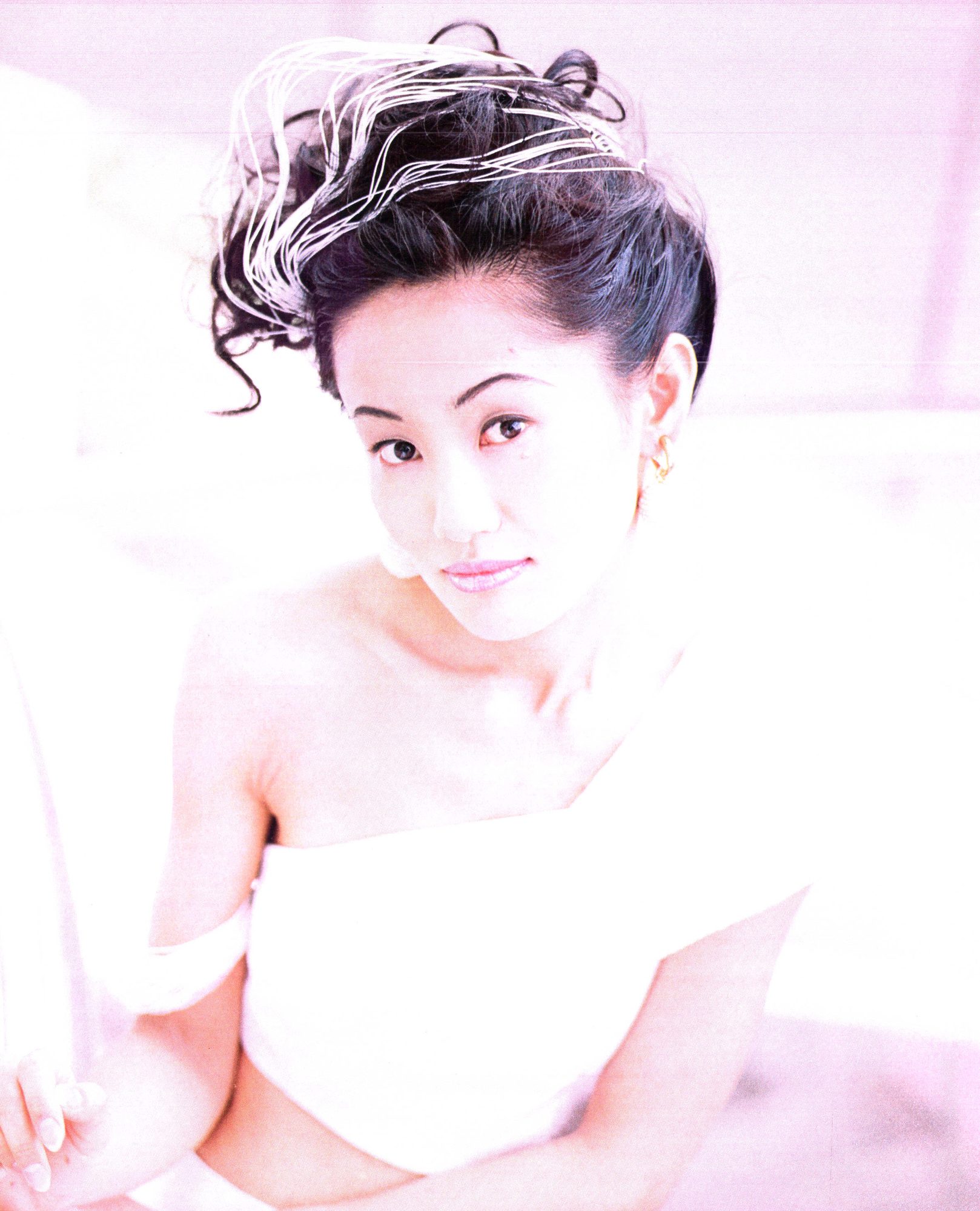 A portrait of Naoko Takeuchi, hair up, shot in pale pink light