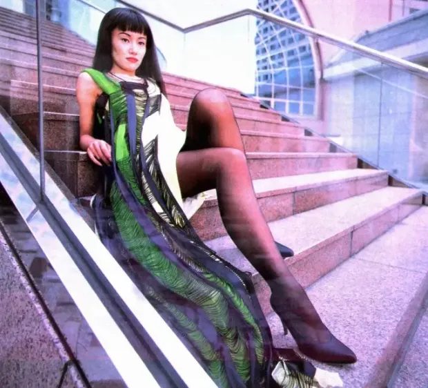 Naoko Takeuchi in a dark patterned dress, seated on a staircase
