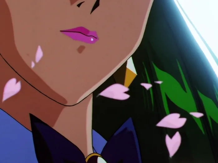 A close shot of Sailor Pluto’s mouth and jaw turned into bright light, her green hair behind her, cherry blossom petals drifting past